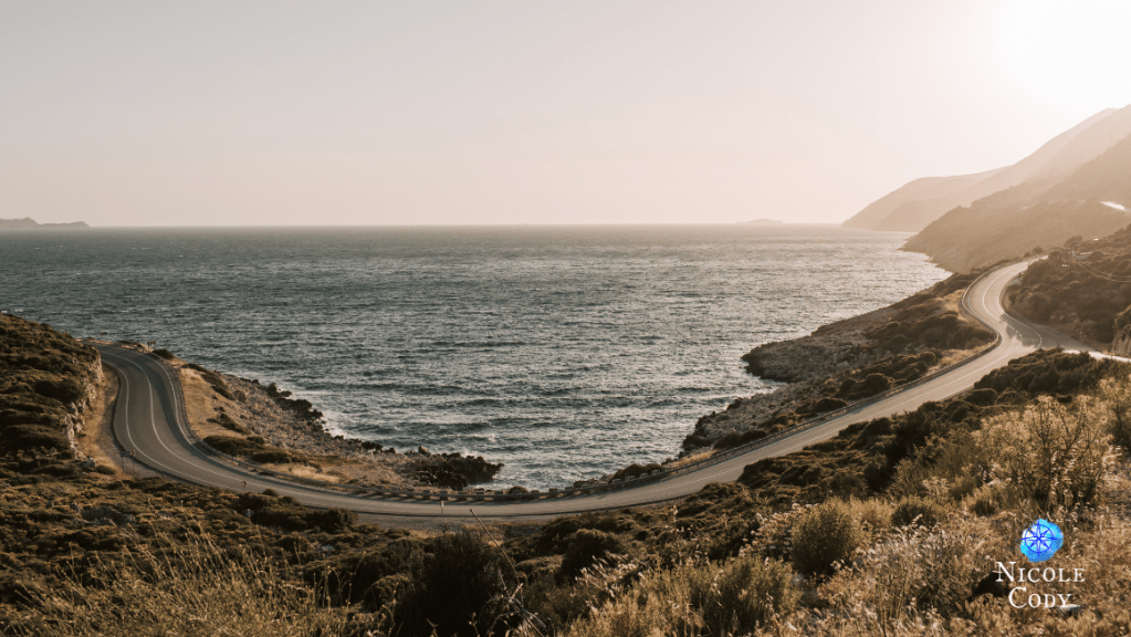 "Coastal road winding beside the ocean under soft afternoon light, symbolising life's journey, reflection, resilience, and finding the way forward."