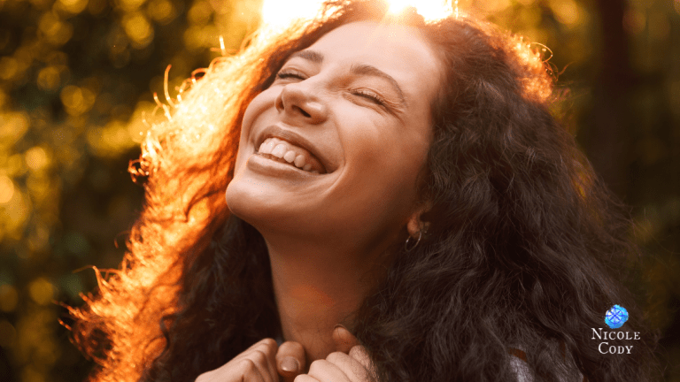 Woman smiling with joy in warm golden sunlight, embracing authenticity, happiness and living true to herself.